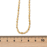 golden oval and round link ball chain necklace displayed over wooden ruler with white background. 