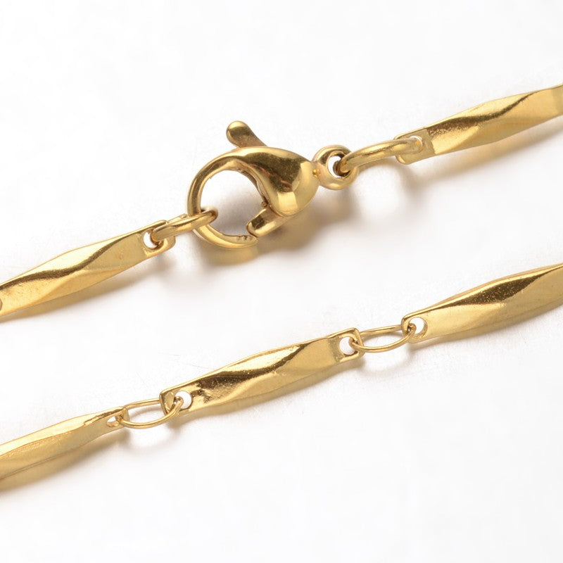 zoomed in sections of golden bar link necklace with lobster claw clasp over white background. 