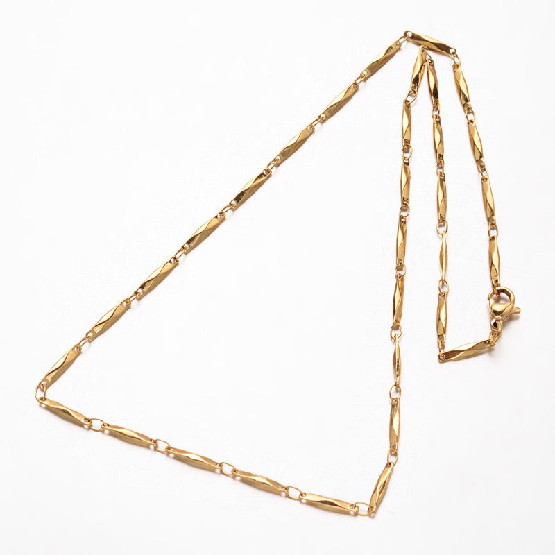 golden bar link necklace with lobster claw clasp over white background. 