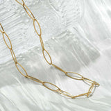 golden marquise paperclip chain necklace with lobster claw clasp and extender chain draped over crystal vase on white tablecloth. 