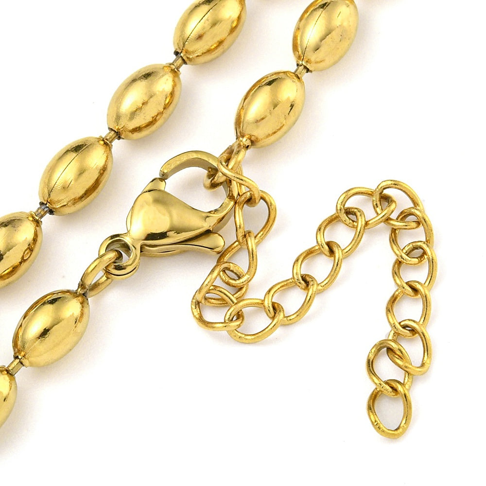 zoomed in section of golden oval ball link necklace with lobster claw clasp and extender chain over white background. 