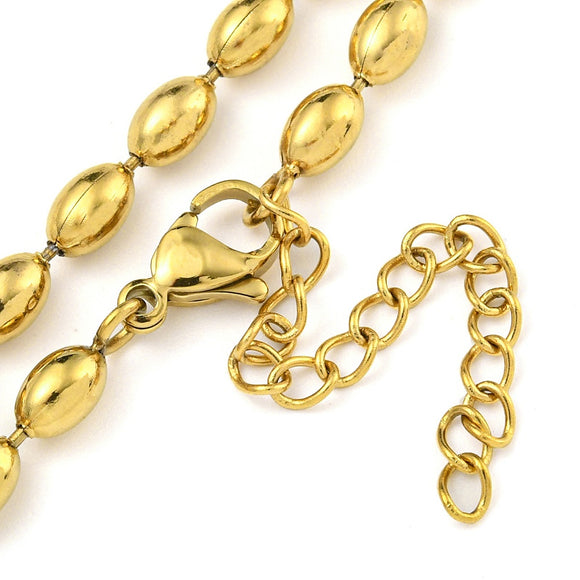 zoomed in section of golden oval ball link necklace with lobster claw clasp and extender chain over white background. 