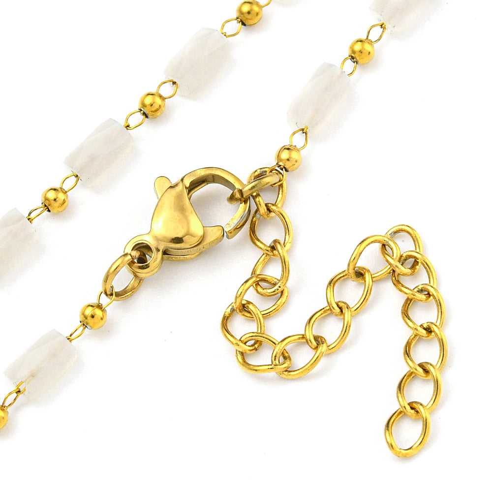zoomed in sections of white glass column link chain necklace with golden lobster claw clasp and extender chain on white background. 