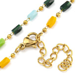 zoomed in sections of multi-colored glass column link chain necklace with golden lobster claw clasp and extender chain on white background. 