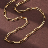 golden square paperclip chain over brown felt surface. 