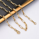golden square paperclip chain draped over black and gold rimmed tray onto white surface. 