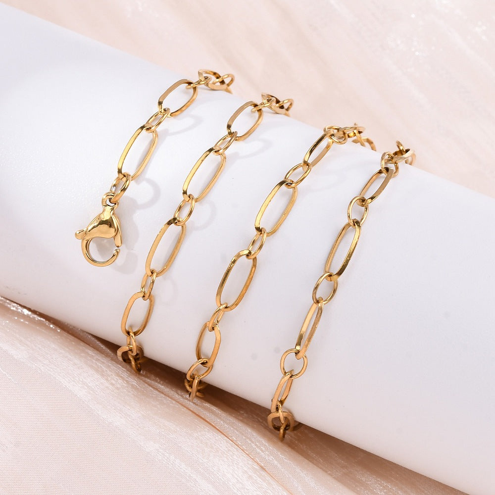 golden alternating oval link chain necklace with lobster claw clasp wrapped around white cylinder over light peach background. 