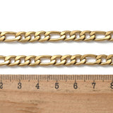 golden Figaro chain necklace with lobster claw clasp displayed above a wooden ruler on a white background. 
