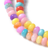 zoomed in section of multicolor dyed shell rondelle beads on white background.