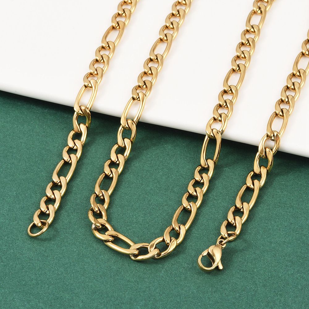 golden Figaro chain necklace with lobster claw clasp draped over a white ledge onto a green felt surface.