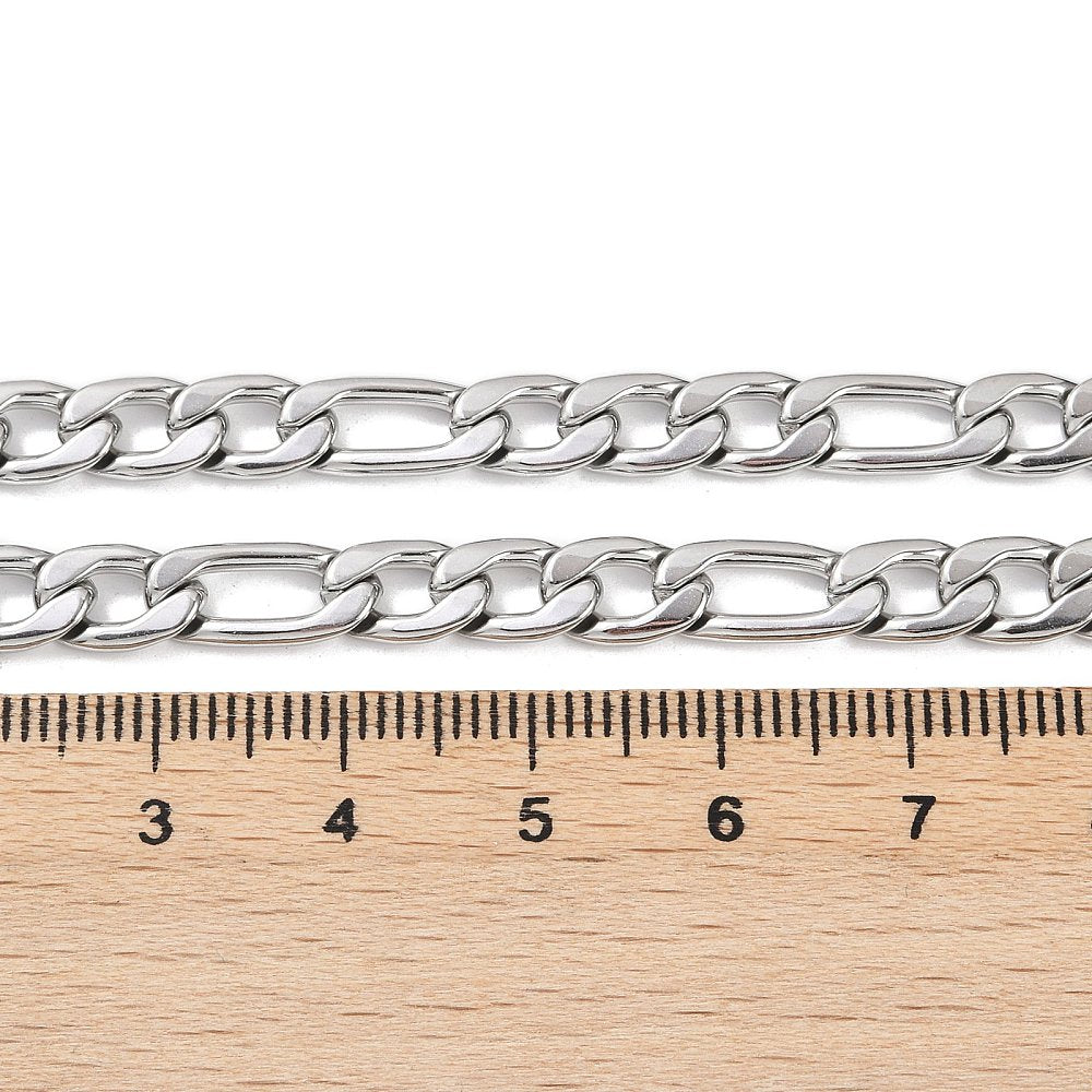 silver tone Figaro chain displayed above  a wooden ruler on a white background. 