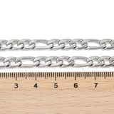 silver tone Figaro chain displayed above  a wooden ruler on a white background. 
