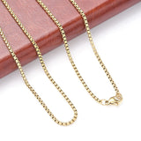 golden Venetian box chain with lobster claw clasp draped over a red leather folder onto a white surface. 