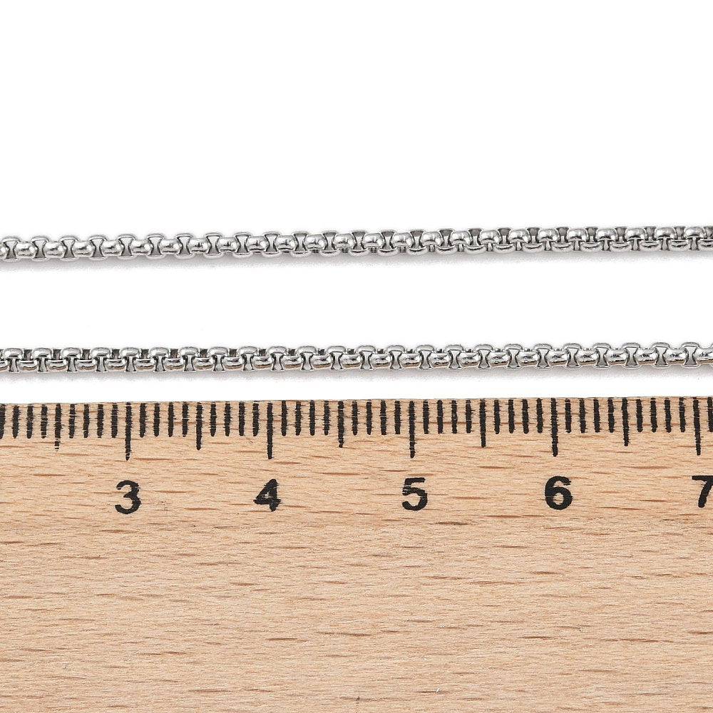 silver tone Venetian box chain displayed above a wooden ruler on white background. 