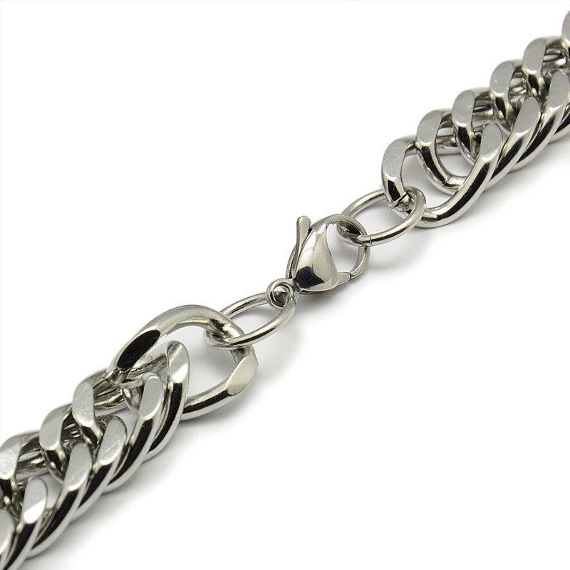 zoomed in section of silver tone lobster claw clasp on large Cuban link chain against a white background. 