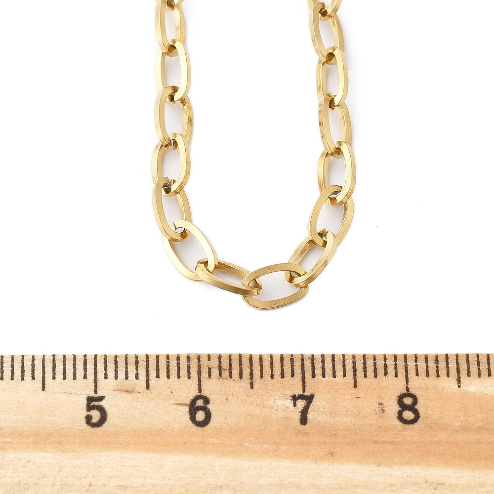 golden oval cable link chain displayed above a wooden ruler on white background. 