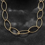 zoomed in section of golden textured horse eye link necklace on black textured background. 