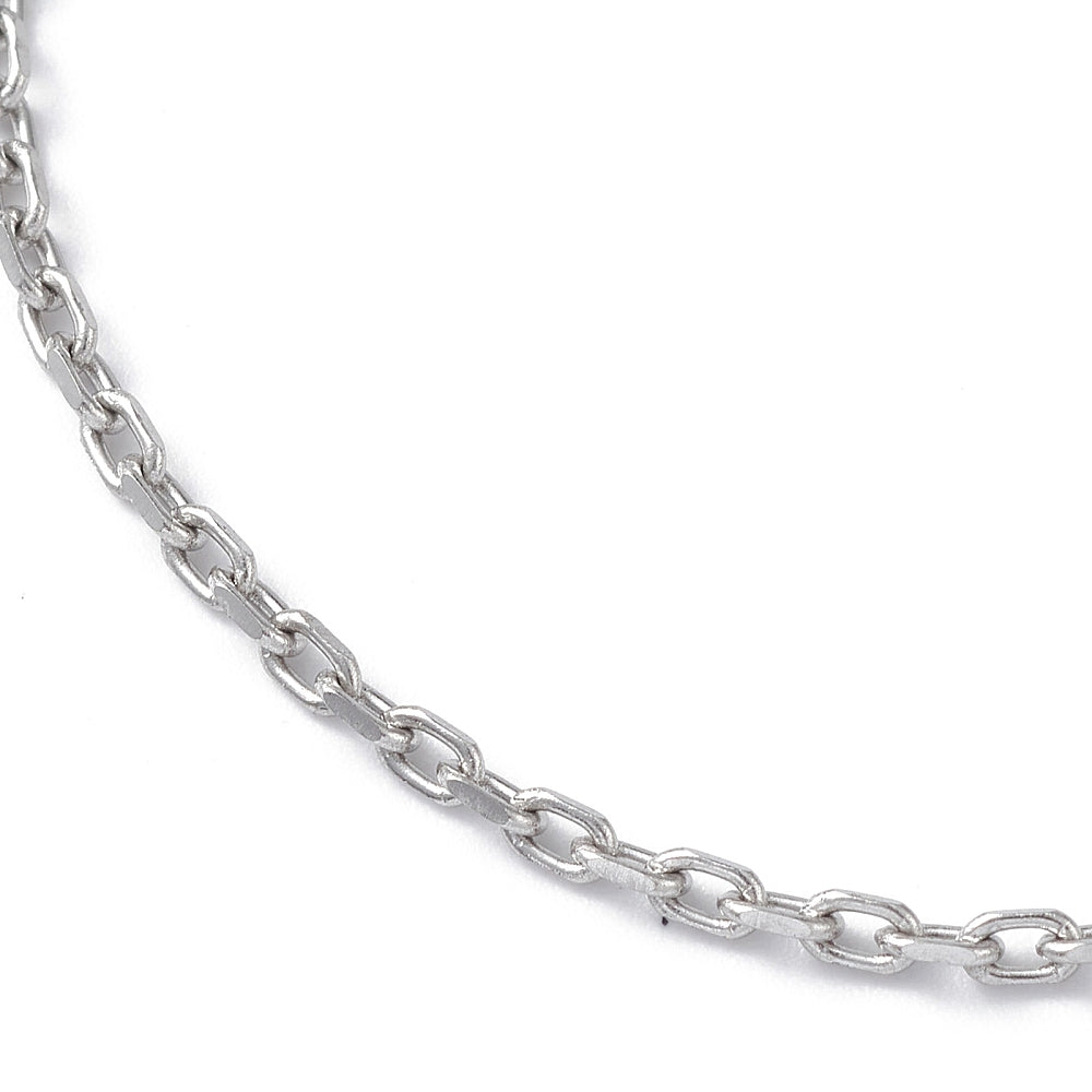 zoomed in section of silver tone cable chain bracelet over white surface. 