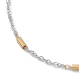 zoomed in section of silver tone cable chain satellite bracelet with golden bar link stations over white background. 