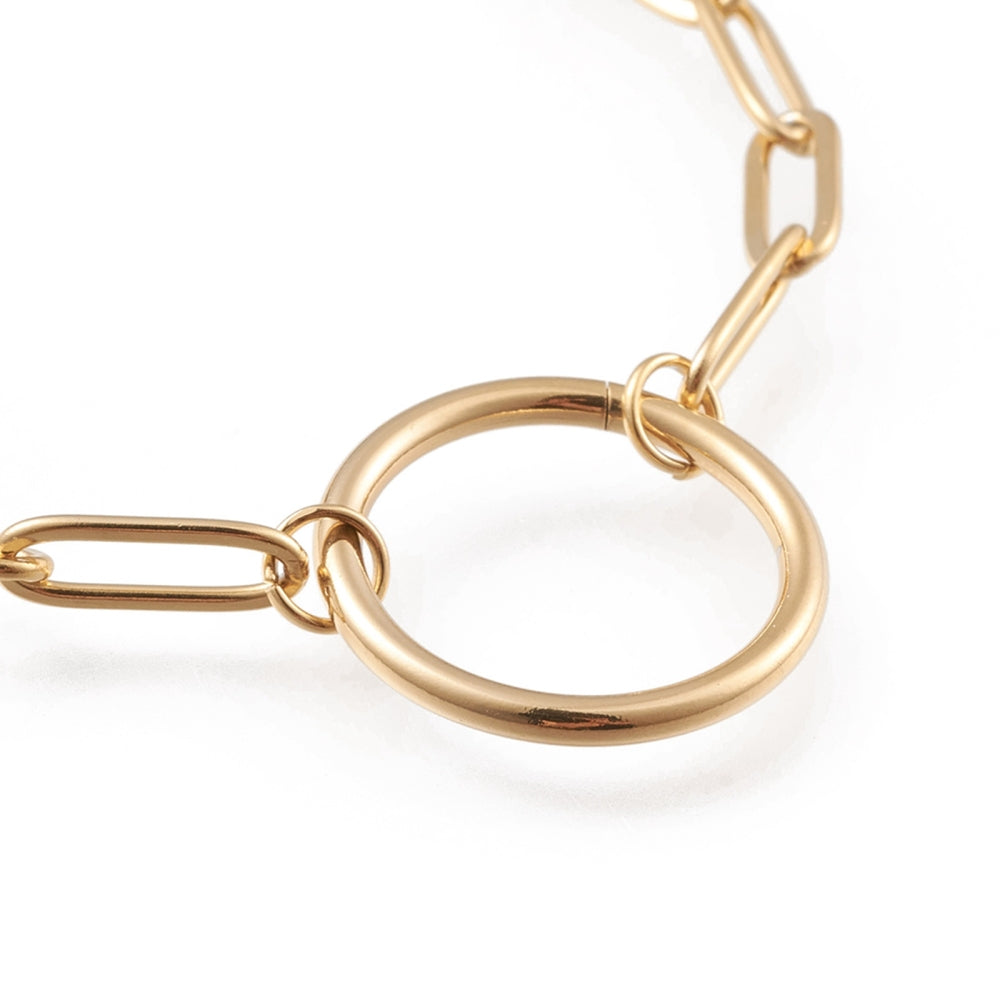 zoomed in section of golden paperclip chain bracelet with ring focal over white background. 