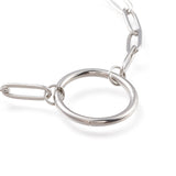 zoomed in section of silver tone paperclip chain bracelet with ring focal over white background. 