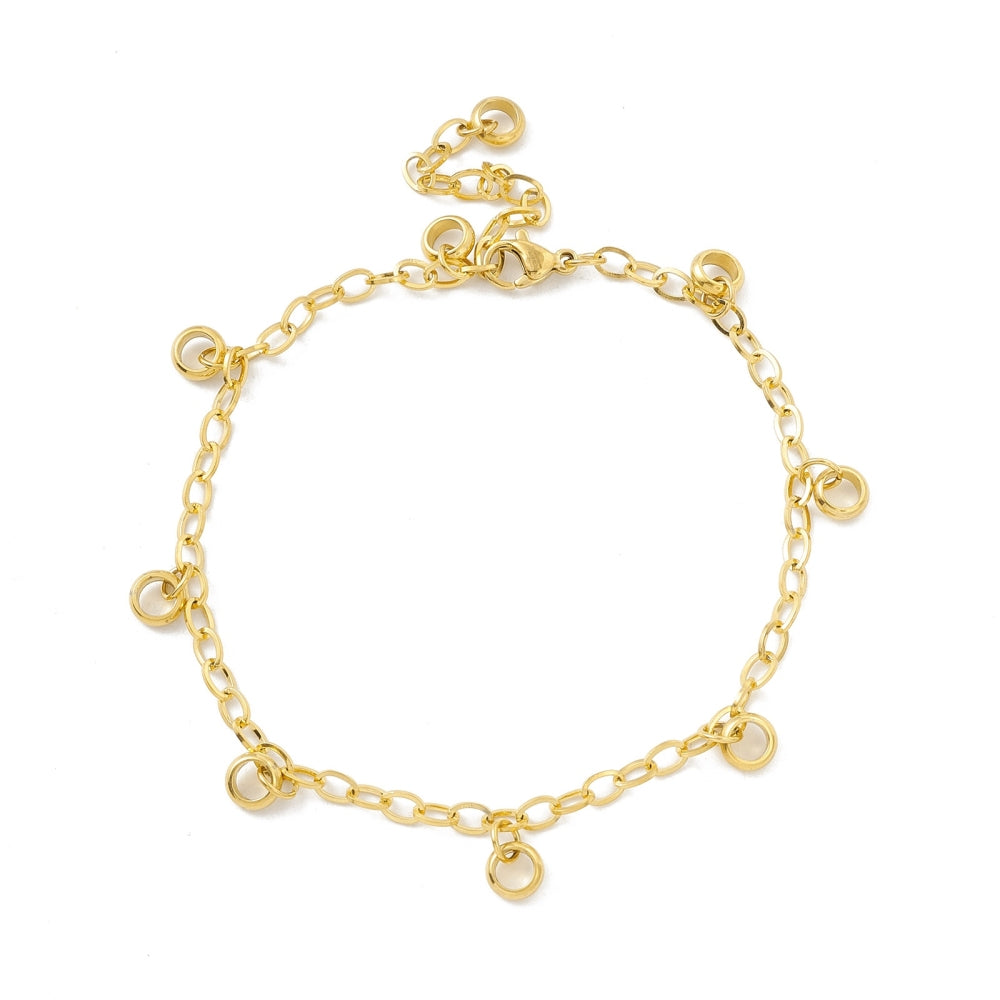 golden add-a-charm bracelet with nine evenly spaced, dangling, soldered jump rings, a lobster claw clasp and extender chain on white background. 