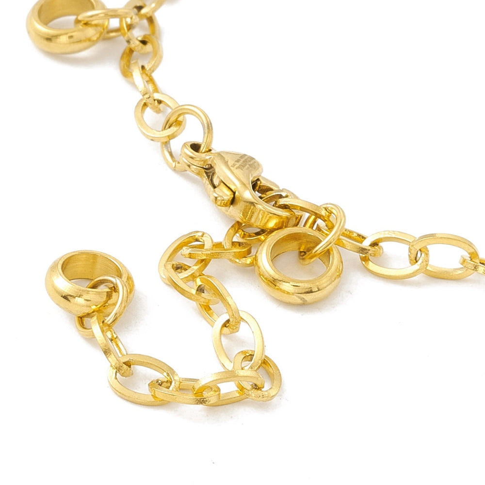 zoomed in section of golden add-a-charm bracelet with evenly spaced, dangling, soldered jump rings, a lobster claw clasp and extender chain on white background. 
