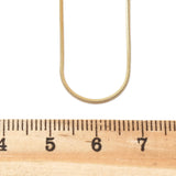 golden square snake chain displayed above wooden ruler on white background. 