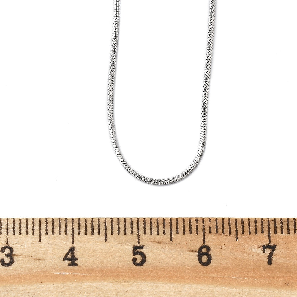 silver tone square snake chain displayed above wooden ruler on white background. 