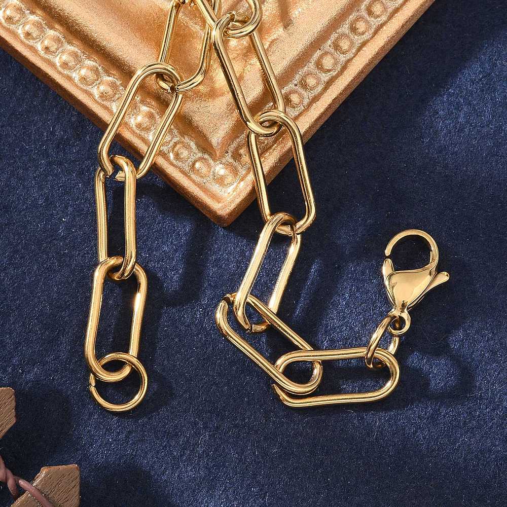 golden rounded paperclip chain bracelet with lobster claw clasp draped over the corner of a golden picture frame over a blue felt background. 