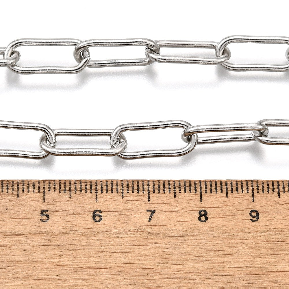 silver tone rounded paperclip chain displayed above a wooden ruler on white background. 