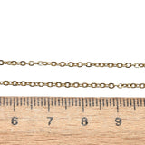 golden fine flat cable chain necklace displayed above a wooden ruler on a white background. 