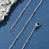 silver tone fine flat cable chain necklace with lobster claw clasp on a blue felt background. 