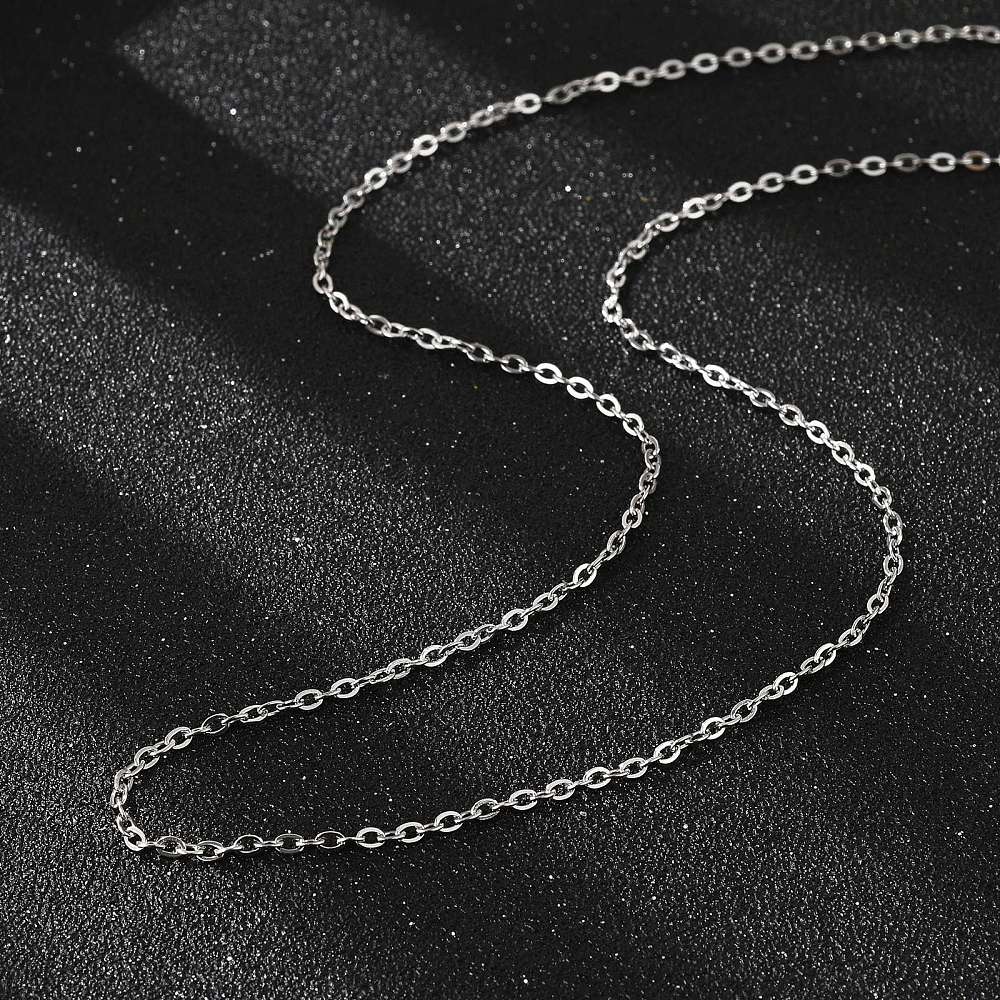 silver tone fine flat cable chain necklace  on a black textured background. 