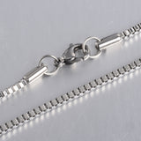 zoomed in sections of silver tone box chain necklace on white background. 