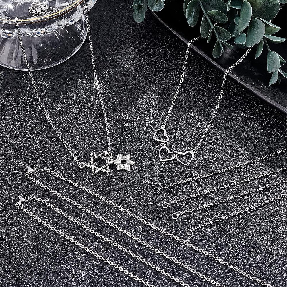 multiple stainless steel cable chain necklaces displayed against a black textured background showing the chain as is or with star or heart connector charms installed. 