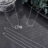 multiple stainless steel cable chain necklaces displayed against a black textured background showing the chain as is or with star or heart connector charms installed. 