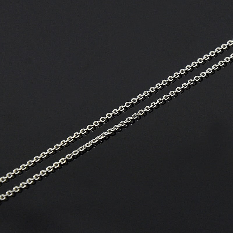 zoomed in section of fine silver cable chain against a black background. 