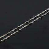 zoomed in section of fine silver cable chain against a black background. 