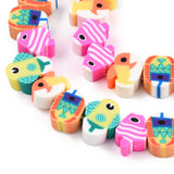 zoomed in section of colorful handmade polymer clay fish bead strands over white background. 