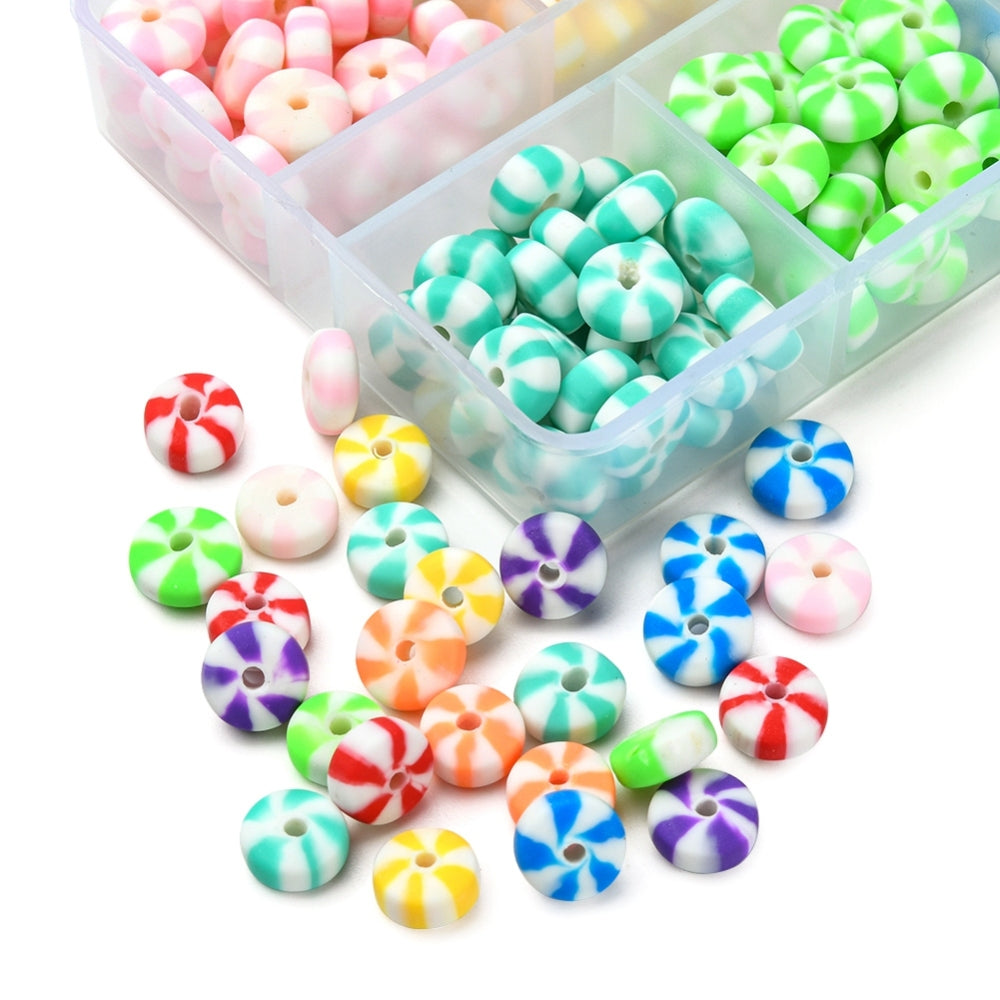 corner of multi-colored candy swirl bead box with beads spilled out onto white surface. 