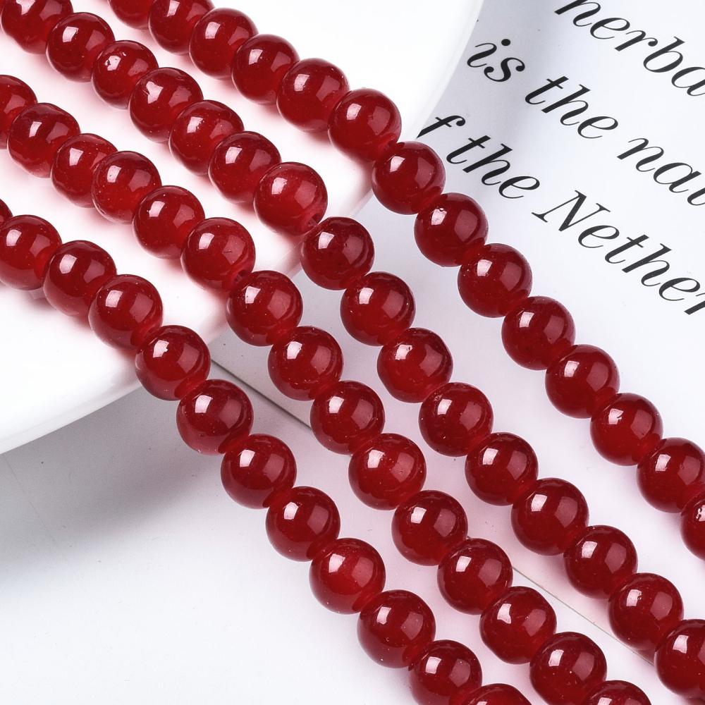 four red round glass bead strands draped white dish ledge onto white paper with black letters. 