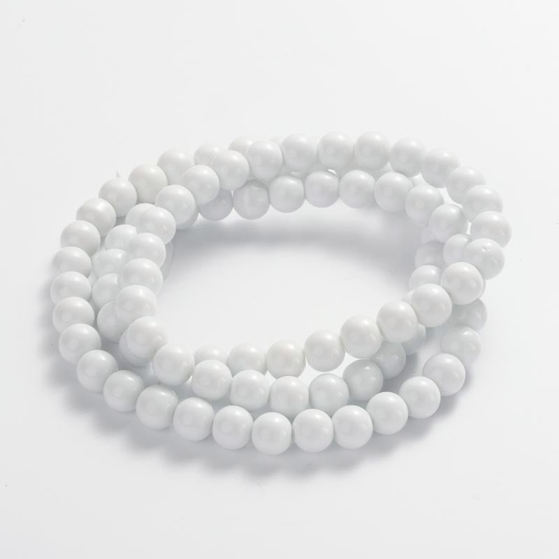 smooth round opaque white bead strand in swirl display over white surface. 