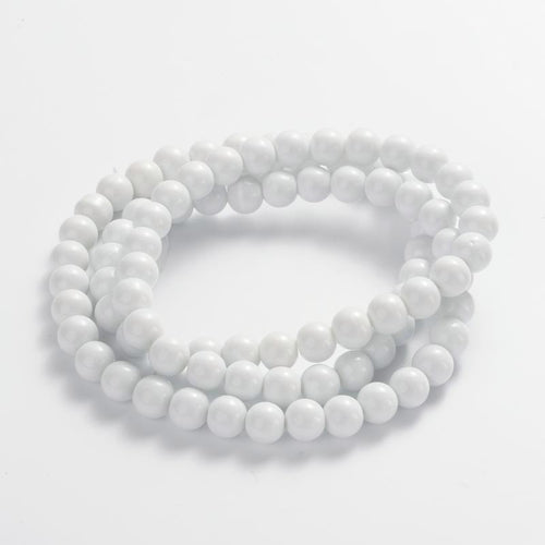 smooth round opaque white bead strand in swirl display over white surface. 