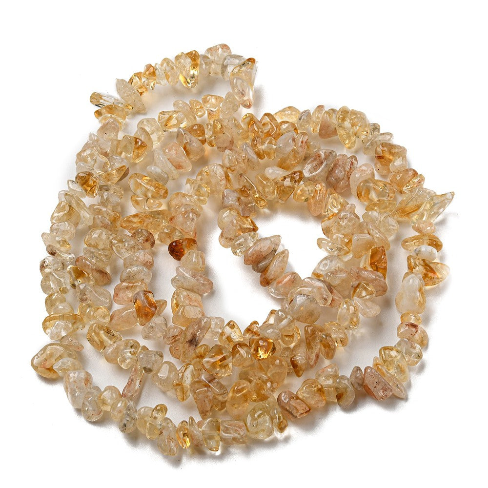 citrine chip bead strand in swirl design over white surface. 