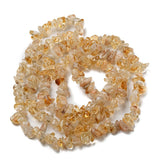 citrine chip bead strand in swirl design over white surface. 