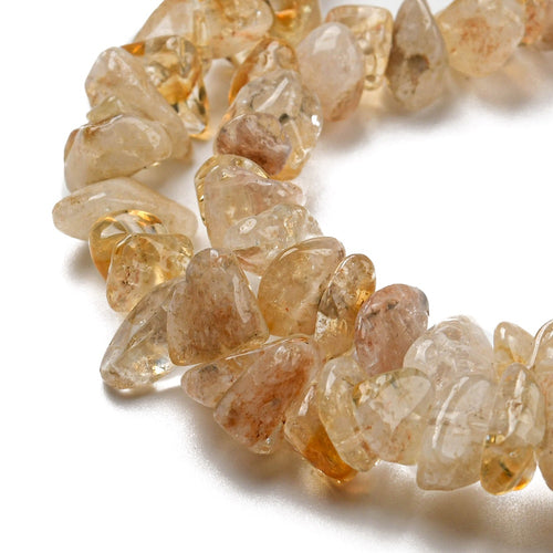 zoomed in sections of citrine chip bead strands over white surface. 