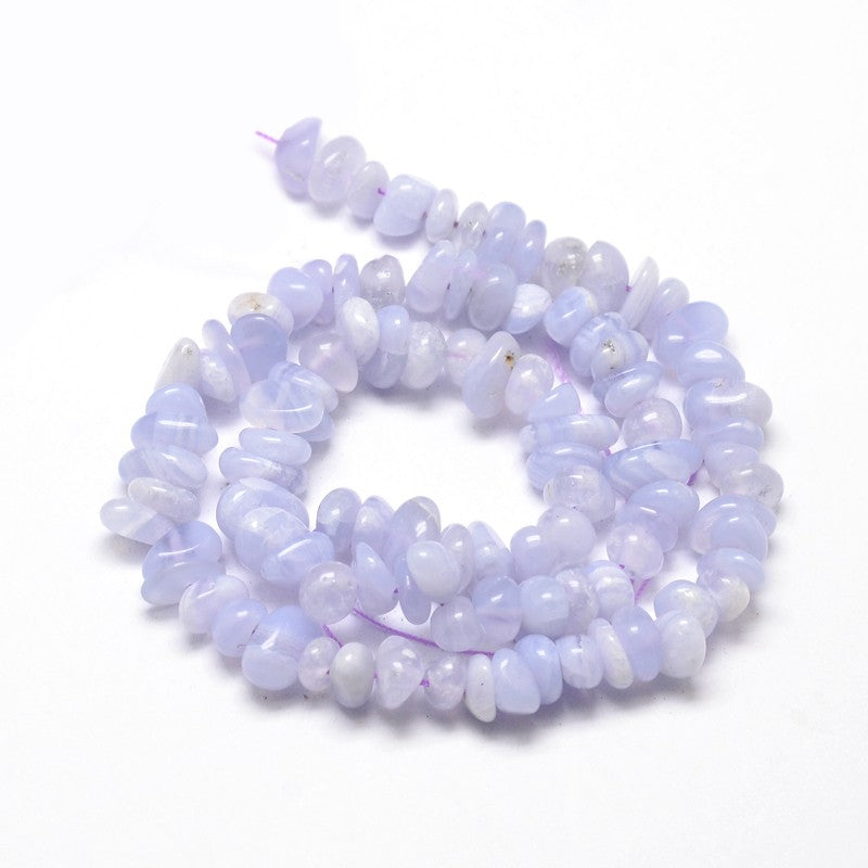 tumbled blue lace agate chip bead strand in a swirl design over white surface. 