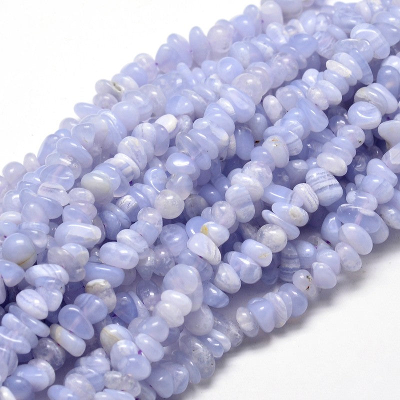 multiple strands of tumbled blue lace agate chip bead over white surface. 