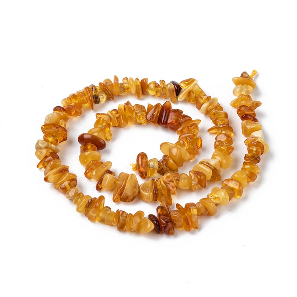 mixed color natural amber chip bead strand in swirl design over white surface. 